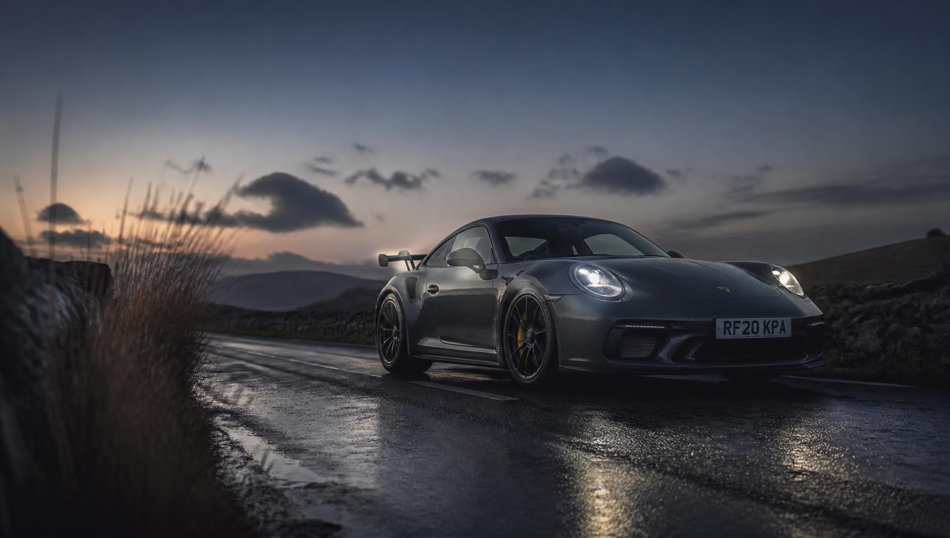 Dark grey performance car on a wet British road at blue hour